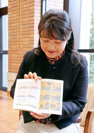 　授業で使用した「尋常小学算術」を手にする同志社女子大の椎名美穂子教授