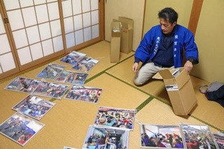 　過去に行われた「敦賀西町の綱引き」の写真を並べる寺田徹也さん＝２０２６年１月、福井県敦賀市