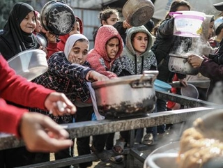 　１月１４日、パレスチナ自治区ガザ中部で、配給の食事を受け取るパレスチナ人＝１４日（ゲッティ＝共同）