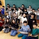 　新巻きザケを手に写真に納まる市立釜石小の児童と斎藤孝信さん（左端）＝２０２５年１２月、岩手県釜石市