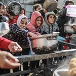 　１月１４日、パレスチナ自治区ガザ中部で、配給の食事を受け取るパレスチナ人＝１４日（ゲッティ＝共同）