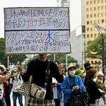 　宮城県知事選で、村井嘉浩氏の演説中に「日本の恥」などと記されたプラカードを掲げる人＝２０２５年１０月、仙台市