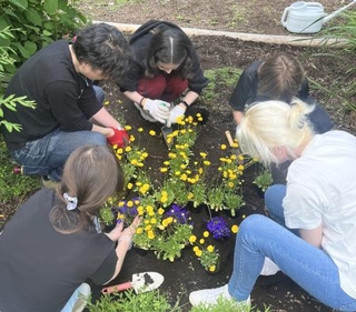 公園の花壇に、平和を祈ってウクライナの国章の形でお花を植える語学教室のメンバー（中央がタヤさん）＝２０２３年６月、札幌市（栄原さん提供）