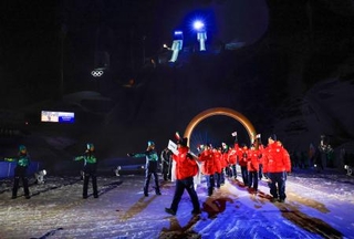 　ミラノ・コルティナ冬季五輪の開会式で入場行進する日本選手団。奥はジャンプ会場＝６日、イタリア・プレダッツォ（共同）