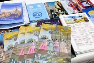 　北京市内の旅行会社で机に広げられた海外ツアー旅行のパンフレット。日本を紹介するものはなかった＝１３日（共同）