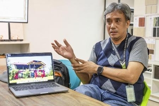 「赤い家」の再建に必要な改修箇所を解説するジョエル・リコさん＝２０２５年１２月、マニラ（共同）