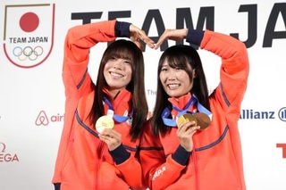 　記者会見でメダルを掲げるスノーボード女子の深田茉莉（左）と村瀬心椛＝２０日、ミラノ（共同）