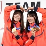 　記者会見でメダルを掲げるスノーボード女子の深田茉莉（左）と村瀬心椛＝２０日、ミラノ（共同）