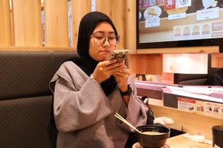 　回転すし屋で注文したラーメンの写真を撮るガヤトリさん＝２０２５年１１月、茨城県神栖市