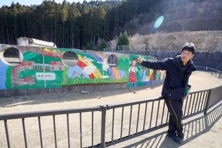 　校庭に立つ佐藤敏郎さん。壁画には「未来を拓く」と書かれている＝２月、宮城県石巻市の旧大川小