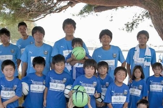 ２０１１年９月、岩手県陸前高田市の高田小を訪れ、子どもたちと写真に納まるサッカーＪ１川崎の選手たち。前列右から４人目が当時の村上力己選手。後列左から２人目が当時川崎のコーチだった寺田周平監督（☆（○の中に小文字のＣ）ＫＡＷＡＳＡＫＩ　ＦＲＯＮＴＡＬＥ）