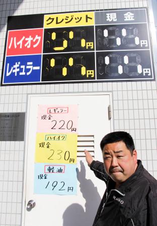　ガソリンスタンド備え付けの看板では１９９円までしか表示できず、急きょ紙に手書きした価格を示す三枝直樹店長＝１６日午後、東京都足立区