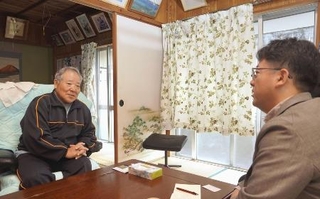 西川征夫さん（左）の話を聞く、明星大の熊本博之教授＝２０２５年１２月、沖縄県名護市