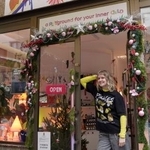 　雑貨店「イレブン・イレブン」の店先に立つロシア人移民のアポリナリア・パホモバさん＝２０２５年１２月、セルビア・ベオグラード（共同）