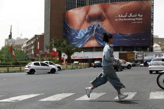 　イラン・テヘランで、トランプ米大統領とホルムズ海峡を描いた看板の近くを歩く女性＝４日（ＷＡＮＡ提供、ロイター＝共同）