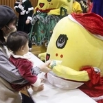 赤ちゃんにクリスマスプレゼントを手渡すふなっしー＝２０２５年１２月２４日、船橋市