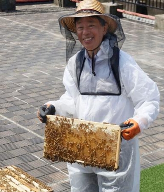 　名古屋市役所の屋上で、蜂蜜が詰まった巣枠を持つ名古屋学院大の水野晶夫教授＝１３日