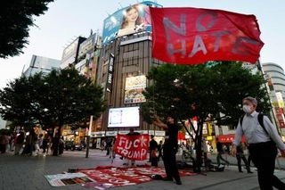 ＪＲ新宿駅東南口で「ＮＯ　ＨＡＴＥ」と書かれた旗を振る鍋倉雅之さん＝５月