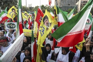 　１２日、イラン・テヘランで国旗などを手に広場に集まった人たち（ゲッティ＝共同）