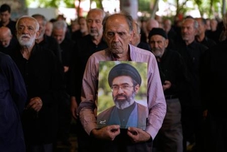 　１９日、イラン・テヘランでの金曜礼拝で、最高指導者モジタバ・ハメネイ師の肖像を掲げる参加者ら（ＡＰ＝共同）