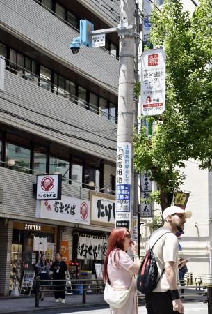 　ＪＲ日暮里駅前の電柱に設置された、顔を識別するＡＩを搭載した防犯カメラ（上）＝５月、東京都荒川区