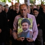 　１９日、イラン・テヘランでの金曜礼拝で、最高指導者モジタバ・ハメネイ師の肖像を掲げる参加者ら（ＡＰ＝共同）