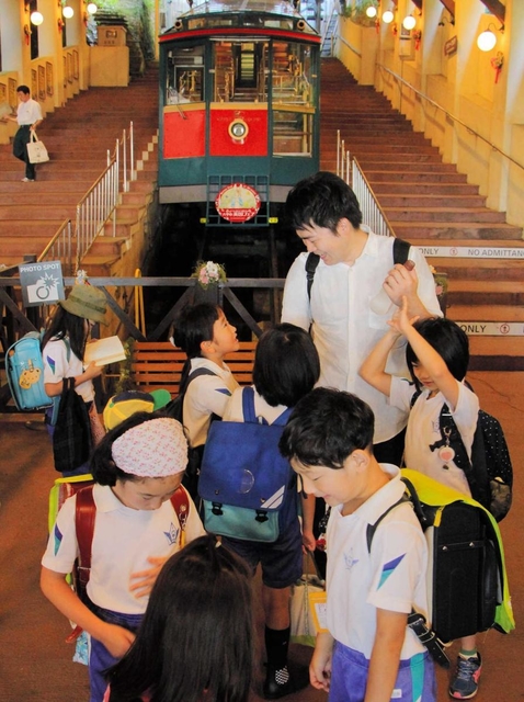 ケーブルカーで、教員と一緒に登校する児童たち＝９日午前、神戸市灘区の六甲ケーブル下駅
