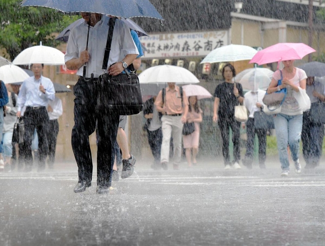 たたきつけるような雨の中、傘を差して歩く人たち＝５日午前、神戸市中央区
