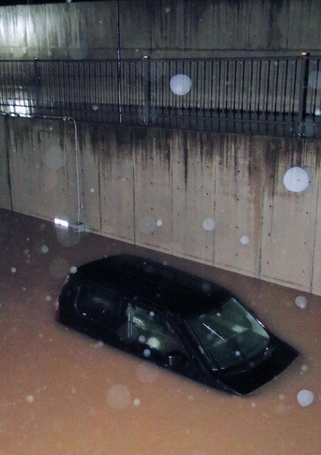 冠水した道路に車体の半分以上がつかった車＝７日午前１時３３分、豊岡市九日市下町（撮影・秋山亮太）