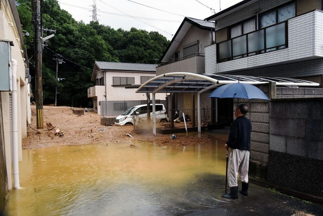 流入した土砂を見つめる住民＝７日午前８時４１分、神戸市灘区篠原台