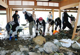 屋内に残った大量の泥や岩をかき出すボランティア＝１０日午前９時５５分、宍粟市一宮町