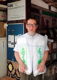 支援物資の土のうを持つ村井雅清さん（被災地ＮＧＯ恊働センター提供）