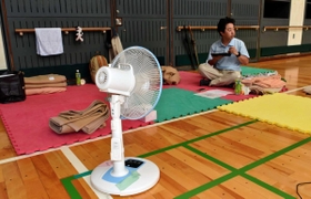空調設備のない体育館で、扇風機で暑さをしのぐ避難者＝１１日午前、神戸市灘区青谷町１