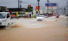 冠水した道路をしぶきを上げて通行する車＝７日午前７時１３分、丹波市氷上町