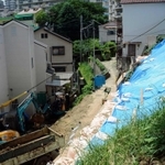 警戒区域外で起きた土砂崩れ。ブルーシートに覆われた斜面から、隣接する民家へ土砂が流れ込んだ＝７月２４日、神戸市長田区上池田３
