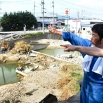 西日本豪雨で岡山県倉敷市真備町を流れる末政川の堤防の決壊場所について説明する男性（左）＝１１日午後４時６分、岡山県倉敷市真備町有井