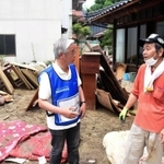 西日本豪雨で岡山県高梁市の川が氾濫し、川沿いの家屋が床上浸水の被害に遭った山口賢治さん（右）の話を聞くひょうごボランタリープラザの高橋守雄所長＝岡山県高梁市落合町阿部　