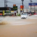 冠水した道路をしぶきを上げて通行する車＝７日午前７時１３分、丹波市氷上町