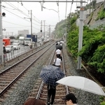 山陽電鉄須磨浦公園－塩屋間で線路上に土砂が流れ込み、立ち往生した電車を降りて線路を歩く乗客ら＝６日午後３時２９分、神戸市垂水区塩屋町