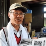 明治時代に下原地区であった水害を記した新聞記事を手に、住民の避難活動を振り返る川田一馬さん＝岡山県総社市下原