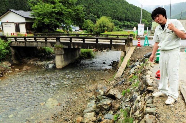 ２年前に流木が詰まった橋の傍らに立つ小林俊介さん。被災した工場は軌道に乗ったが、橋の架け替えが終わるまで気が休まらない＝宍粟市一宮町