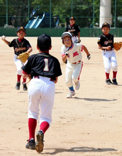 ランナーを挟むけやき坂グリーンファイターズの選手たち＝西宮中央運動公園野球場