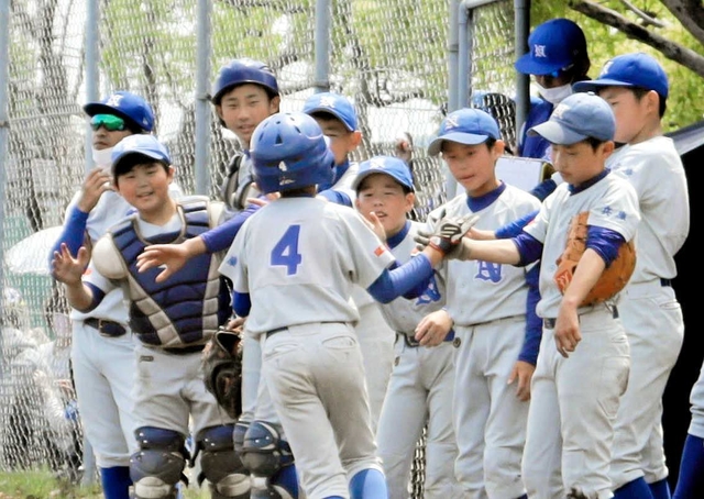 生還したランナーを笑顔で迎える西脇野球スポーツ少年団の選手ら＝大池総合公園野球場