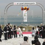 明石海峡大橋を背景に、くす玉を割って開通１０年を祝う式典出席者＝５日午前、淡路市岩屋の神戸淡路鳴門自動車道・淡路サービスエリア（撮影・峰大二郎） 