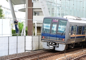 事故現場を通過する列車。会場は目隠しの布で覆われる中、車内の車掌が黙礼していた＝２５日午前７時５４分、尼崎市久々知３（撮影・中西幸大）