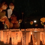 脱線事故の犠牲者を追悼してろうそくに火をともす参加者ら＝２４日夜、尼崎市久々知３（撮影・秋山亮太）