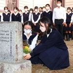石井勝さんの顕彰碑に花を手向ける吹奏楽部の生徒＝三田学園
