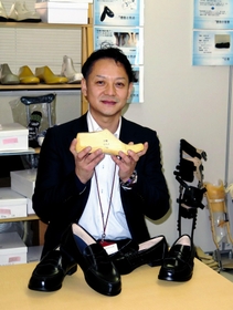 学生向けの医療用整形靴を前に、開発した思いを語る藤原誠文さん＝魚住町金ケ崎
