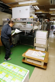 ８色印刷が可能な印刷機と作業する従業員（左）＝明石市樽屋町