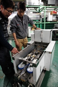 冷凍の魚で製品をチェックする真利社長（左）と従業員＝いずれも明石市二見町西二見